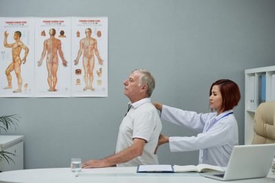Physiothrapist checking spine of senior man in her office